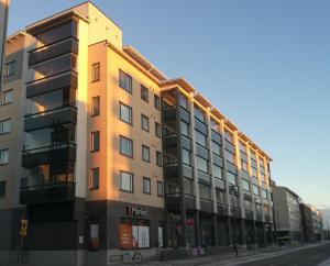 a building on a street with the sun shining on it at RovaVisit Apartments Paroni in Rovaniemi
