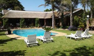 a group of chairs sitting around a swimming pool at Amani Guest Lodge in Port Elizabeth
