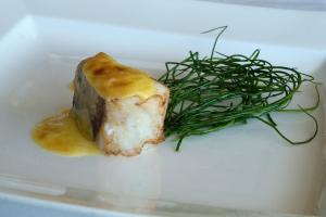 a piece of food on a white plate with a green plant at Hotel Emporda in Figueres