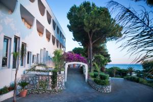 a building with a pathway next to the ocean at Hotel Sinuessa Terme in Mondragone