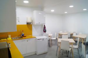 a kitchen with white cabinets and tables and chairs at Alberguinn in Barcelona +21 photos