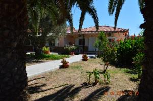 a house with palm trees and flowers in a yard at Garden View Apartments in Anaxos