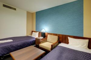 een hotelkamer met 2 bedden en een stoel bij Hotel Taira in Naha