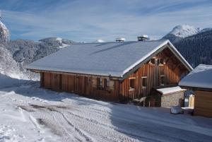 a wooden cabin with snow on the roof at Le Roy des Montagnes à la Ferme des Ramus in Les Gets