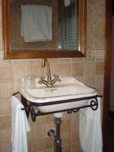 a sink in a bathroom with a mirror and towels at Hotel Rural El Caseron de Linarejos in Linarejos