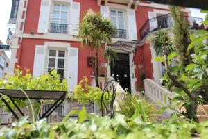 a red and white house with plants in front of it at Hôtel & Espace Bien-être La Maison du Lierre in Biarritz