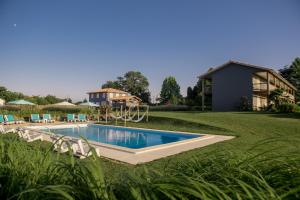 uma piscina num quintal com parque infantil em Hotel Lodge La Petite Couronne em Saint-Cricq-Chalosse