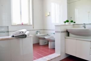 a white bathroom with two sinks and a toilet at Appartamento da Andrea in Alcamo