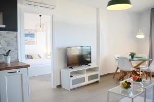 a white living room with a television and a table at Duquesa de España in Torremolinos
