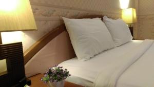 uma cama com almofadas brancas e flores numa mesa em Salsa Hostel em Chumphon