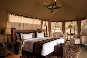 een slaapkamer met een bed in een tent bij Ole Serai Luxury Camp in Serengeti