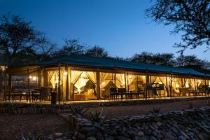 une grande tente avec des tables et des chaises la nuit dans l'établissement Ole Serai Luxury Camp, au parc national du Serengeti