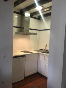 - une cuisine blanche avec évier et cuisinière dans l'établissement Apartamentos La Casona, à Ucieda de Arriba