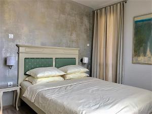 ein Schlafzimmer mit einem großen Bett mit weißer Bettwäsche und Kissen in der Unterkunft Penthouse Tsarevets in Weliko Tarnowo