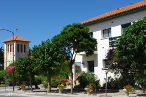 un bâtiment avec une tour d'horloge à côté d'une rue dans l'établissement Hotel des Pins, à Soulac-sur-Mer