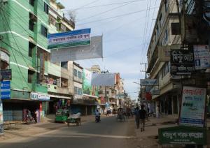 a city street with people walking down the street at Hotel Asia in Cox's Bazar
