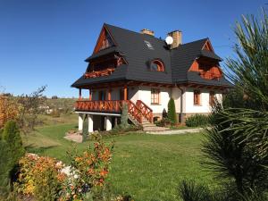 une maison avec un toit noir sur une cour verte dans l'établissement Willa Grandeus, à Bukowina Tatrzańska