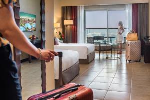 a woman standing in a hotel room with a suitcase at Khalidiya Palace Rayhaan by Rotana, Abu Dhabi in Abu Dhabi