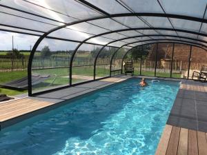 a swimming pool under an enclosure with a person in the water at Le Grand Gîte in Dorengt