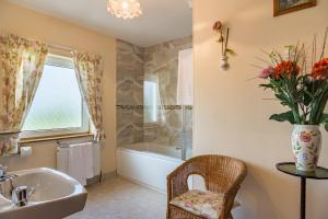 a bathroom with a tub and a sink and a vase of flowers at Ballindrum Farm B&B in Athy