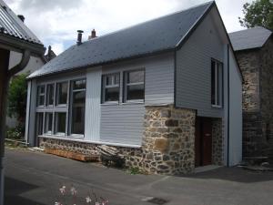 ein graues Haus mit einer Steinmauer in der Unterkunft Gîte très lumineux in Vernines