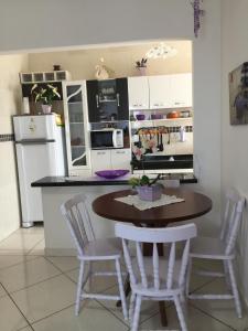 a kitchen with a table and chairs and a refrigerator at Residencial Viamar in Praia Grande