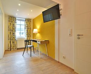 a room with a desk and a television on a wall at Hotel zur goldenen Sonne in Usingen