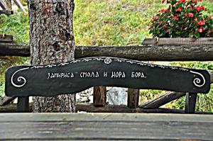 a bench with writing on it next to a tree at Etno kuće Boškova Voda in Zlatibor