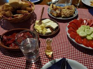 una mesa con platos de comida en un paño de mesa blanco y rojo en Etno kuće Boškova Voda, en Zlatibor
