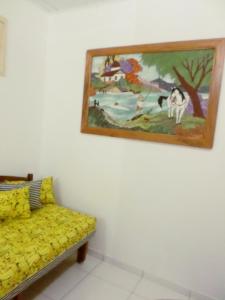 a yellow couch in a room with a painting on the wall at Casa para temporada in Prado