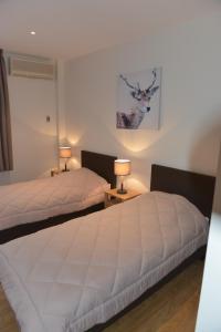 two beds in a bedroom with two lamps on tables at Pyrenees Resort in Argelès-Gazost