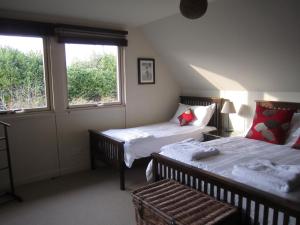 two beds in a room with two windows at Hare Lodge B&B in Tisbury