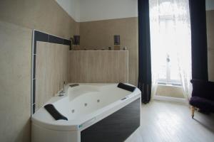 La salle de bains est pourvue d'une grande baignoire blanche et d'une fenêtre. dans l'établissement Chambres d'Hotes La Chartreuse des Eyres, à Podensac