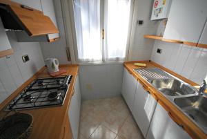 a small kitchen with a sink and a stove at Villetta Vela in Lignano Sabbiadoro