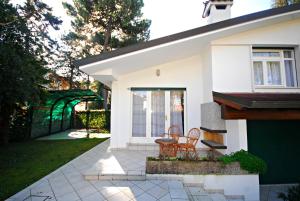 een wit huis met 2 stoelen en een patio bij Villetta Vela in Lignano Sabbiadoro