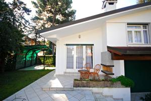 a white house with two chairs and a patio at Villetta Vela in Lignano Sabbiadoro