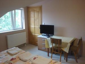 a room with a table and a desk with a television at Sissy Vendégház in Mórahalom