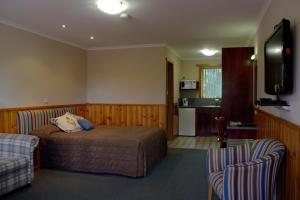 a bedroom with a bed and a tv and two chairs at Kentish Hills Retreat in Sheffield