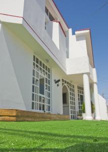 a white house with a green lawn at Le Prince Apart Tacna in Tacna