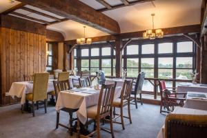 a dining room with tables and chairs and windows at The Swan Inn by Innkeeper's Collection in Horning
