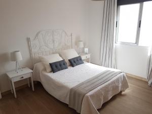 Un dormitorio blanco con una cama grande con almohadas azules. en El Lomo, en Santa Cruz de la Palma