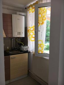 a kitchen with a window with yellow and white curtains at Casa Oprea in Sinaia +9 photos