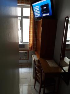 a room with a tv and a desk with chairs at Hotel Ferreira Viana in Rio de Janeiro