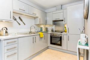 een witte keuken met witte kasten en apparaten bij 3, Gainsborough House in Cheltenham