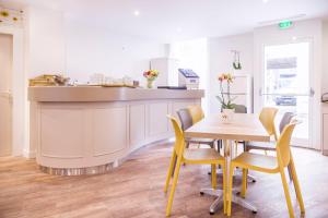 a kitchen with a wooden table and yellow chairs at Hotel Des Arts in Rueil-Malmaison