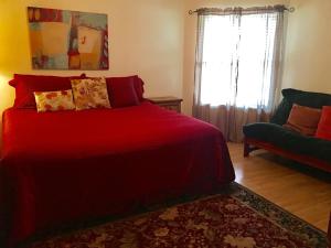 a bedroom with a red bed and a couch at River Run Retreat in New Braunfels