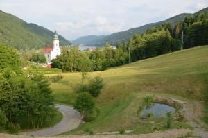 a church on the side of a hill with a pond at Haus Donaublick in Engelhartszell