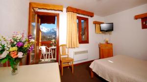 ein Hotelzimmer mit einem Bett und einer Vase aus Blumen in der Unterkunft Résidence La Rochetaillée in Brides-les-Bains