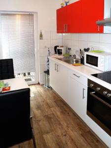 cocina con armarios rojos y suelo de madera en Ferienwohnung Anke - Apartment 3a, en Heinsberg