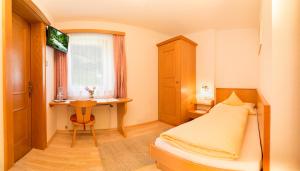 a bedroom with a bed and a table and a window at Haus Sonnenseit'n in Neustift im Stubaital